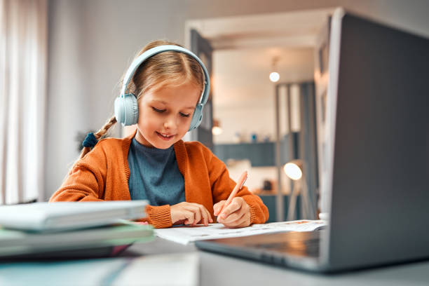 istock Kids using technology. Smiling elementary student sitting in front of laptop and listening to audio 2131160501
