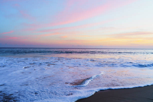 Serene beach scene adorned with the warm hues of a setting sun, casting a mesmerizing glow over the shoreline