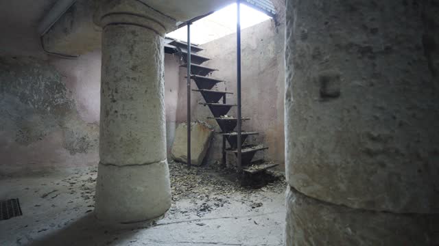 Slow revealing shot of a metal ladder leading to antique stone pillars