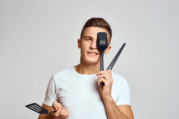 istock Guy with kitchen tools in hands on a light background cropped view of emotions fun model 2131215741