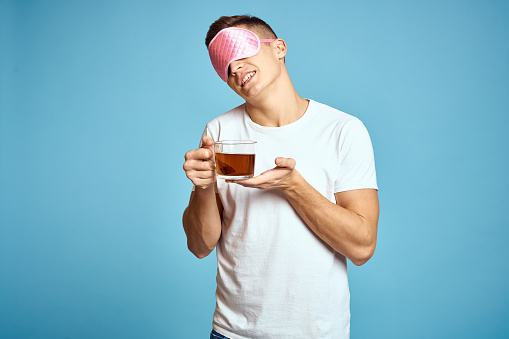 man with pink sleep mask and cup of tea drink cheerfulness model breakfast. High quality photo