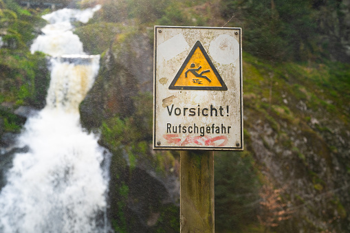 Slippery warning sign, Triberg waterfall in the Black Forest, highest fall in Germany, Gutach river plunges over seven major steps into the valley