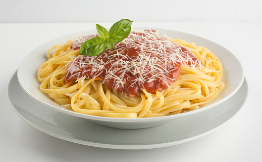 Linguine with tomato sauce, parmesan cheese and basil leaves. White background. Studio shot.