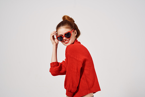 fashionable woman in sunglasses on a light background and red sweater model makeup. High quality photo