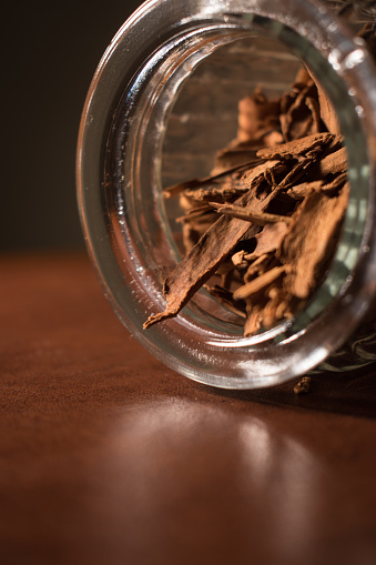 Close up of some cinnamon sticks in a glass pot on a brown table