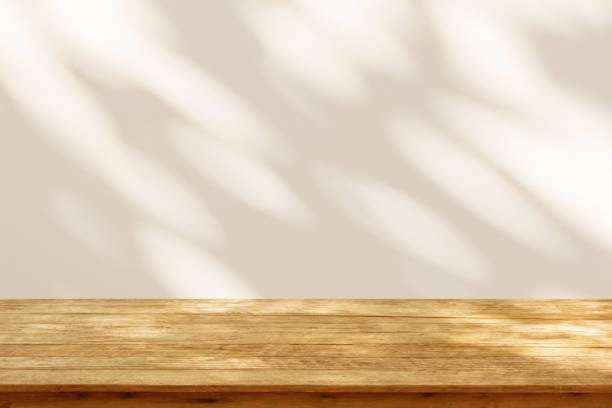 istock Empty wood table top on beige wall texture with tree leaves shadow background 2131374548