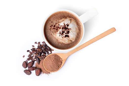 Mug of chocolate drink and cocoa powder with cacao beans in wooden spoon isolated on white background. Top view. Flat lay.