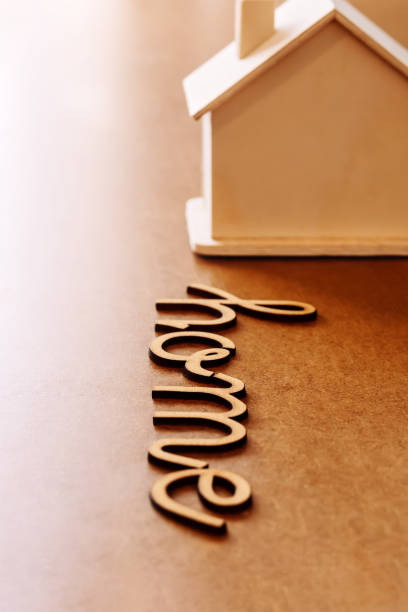 A small house model emitting smoke, placed near the word âhomeâ, on a warm background.