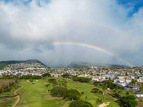 Aerial view of Honolulu and the cloudy mountains with a rainbow in the background. Oahu, Hawaii