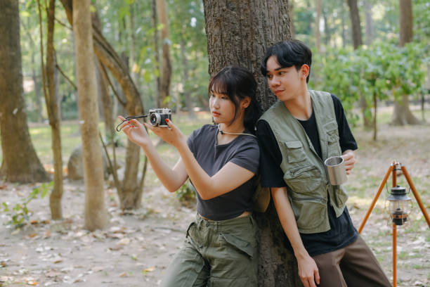 istock Asian couple clinking coffee mug together at camp side, They feeling relaxed and refreshing while camping in the nature. Recreation 2131490173