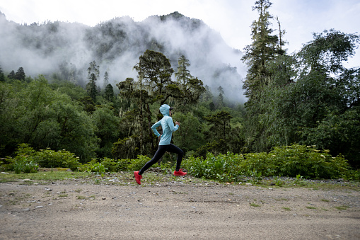 Woman trail runner cross country running in high altitude mountain forest