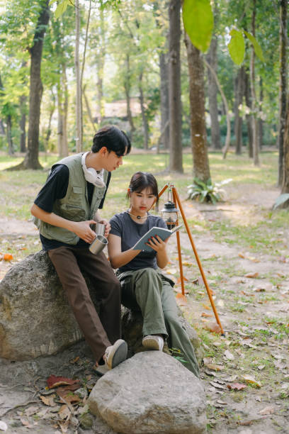 istock Asian couple clinking coffee mug together at camp side, They feeling relaxed and refreshing while camping in the nature. Recreation 2131490204