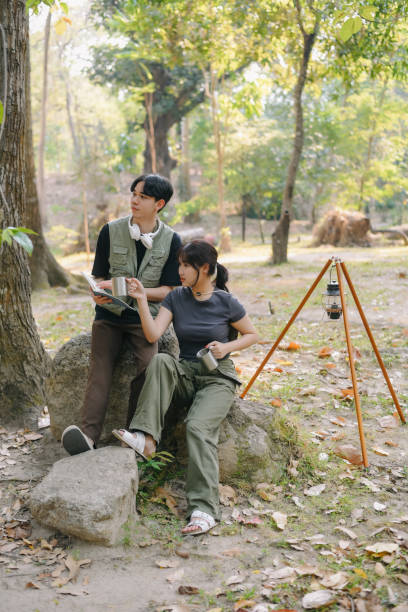 istock Asian couple clinking coffee mug together at camp side, They feeling relaxed and refreshing while camping in the nature. Recreation 2131490212