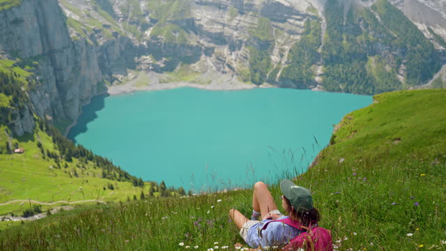 Woman laying on the meadow near the hiking trail in Switzerland