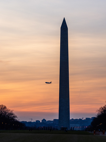 Washington monument counter exposed during sunset with plane flying behind