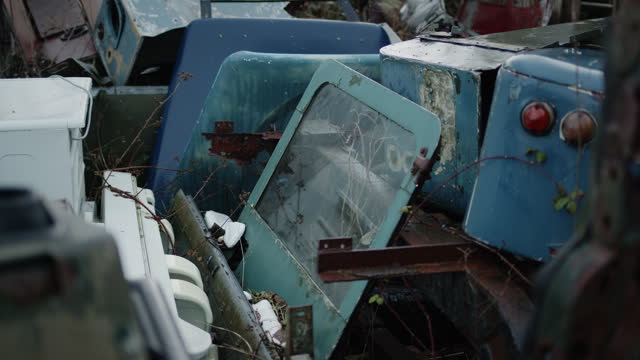 Trash at dumpyard. Car door among pile of abandoned objects. Handheld outside