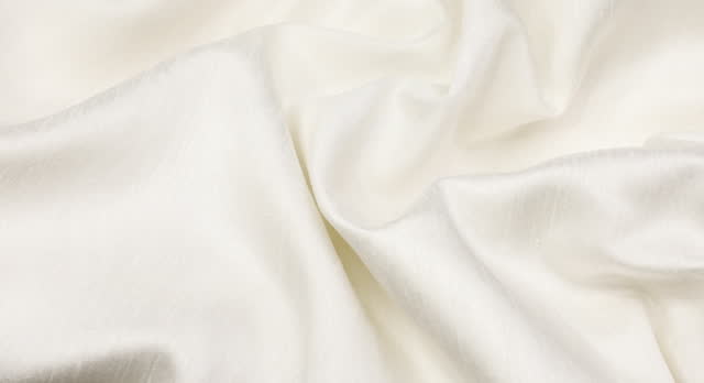 White fabric background. White cloth waves background texture. White fabric cloth textile material.