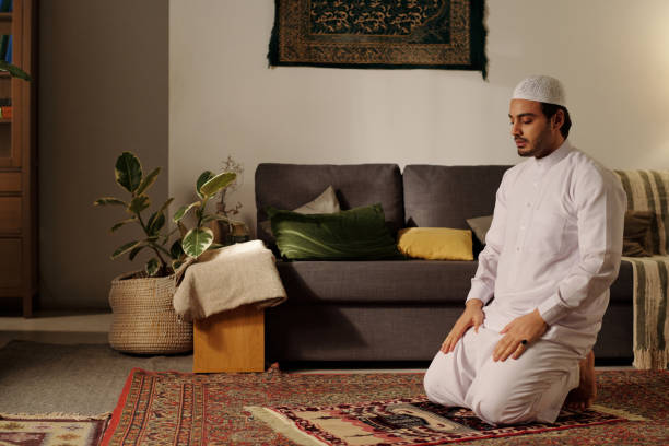 istock Young Muslim Man Praying In Living Room 2131776012