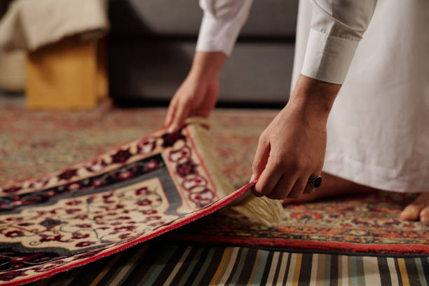 istock Unrecognizable Muslim Man Placing Prayer Mat On Floor 2131776014