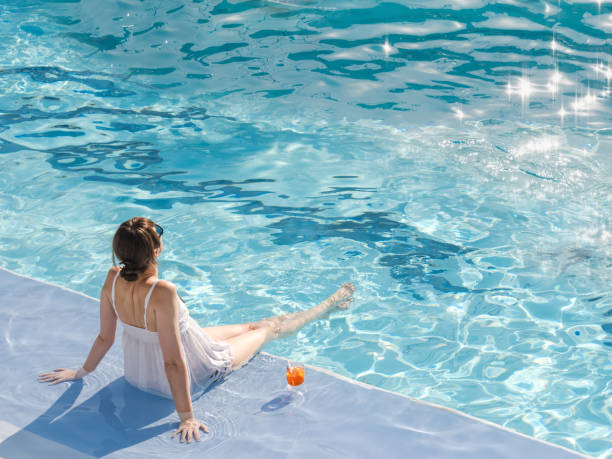 Cute woman with a glass of drink Cute woman with a glass of drink sits near the swimming pool of a cruise ship. Sunny, clear morning. View from above. Closeup, outdoors. Vacation and travel concept arabian sunglasses stock pictures, royalty-free photos & images