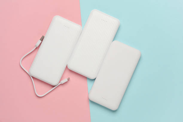 istock White power banks with cable on pink blue background. External batteries for charging smartphone and other gadgets. Top view 2131795266