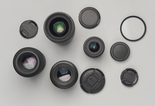 Professional camera lenses with filters and caps on a gray background. Top view