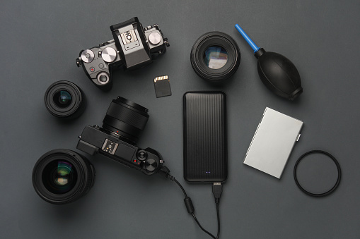 Minimalistic set of professional photographer equipment on a dark gray background. Modern mirrorless camera and accessories. Flat lay