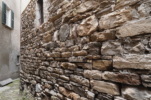 View of a glimpse an alley in Italy, highlighting an ancient wall built with the dry method. Careno area, Lake Como, Italy