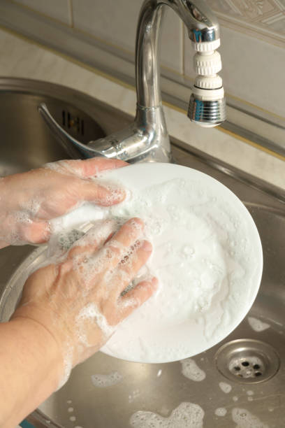 istock woman washing dishes in the kitchen 2131803265