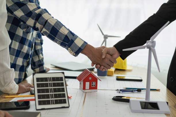 istock Yellow hard hat on table and house design print design with construction team handshake greeting start new project contract plan in office center at construction site partner and contractor 2131804345