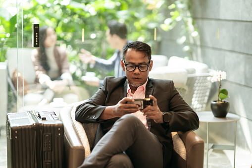 Asian Malay male businessman using mobile in an airport lounge