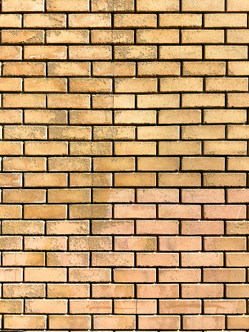Blank yellow brickwall background, texture. Empty aged dirty worn grunge brick wall masonry for backdrop. Ad template, copy space. Vertical