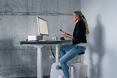 businesswoman working at ergonomic workplace on desk bike at home on computer