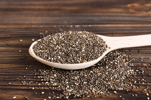 Wooden spoon and chia seeds on colored background, top view. Healthy Salvia hispanica Healthy superfood.