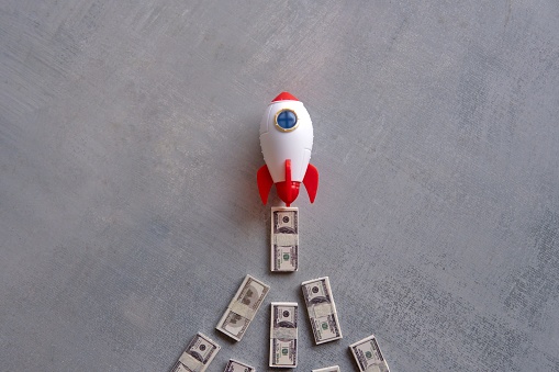 Rocket blasts off through a pile of money. Skyrocket sales, growing sales concept.
