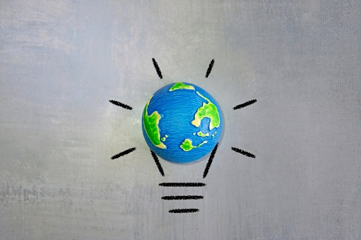 Drawing of glowing lightbulb and world globe with copy space. Earth hour, renewable energy concept.
