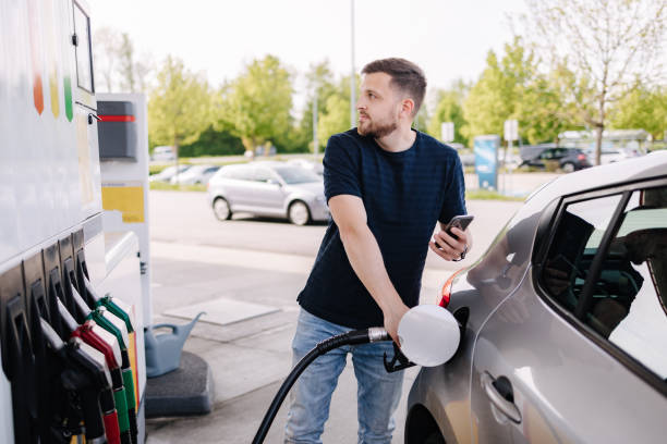 istock Handsome bearded man refueling car and looking on the scoreboard while standing on self service gas station 2131965324