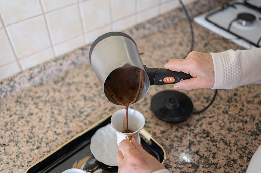 Senior Woman Pouring Turkish Coffee In To A Cup At Home