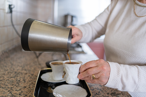 Senior Woman Pouring Turkish Coffee In To A Cup At Home
