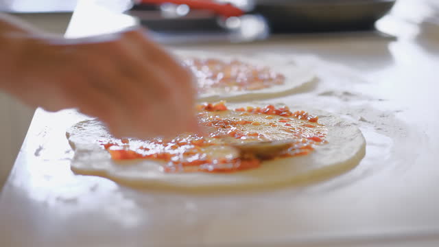 Video of cooking Italian homemade closed pizza - calzone, the cook applies tomato paste on a flatbread of dough