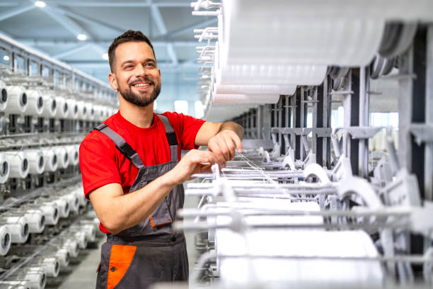 istock Experienced textile factory worker checking thread on sewing machine production line. 2132010017