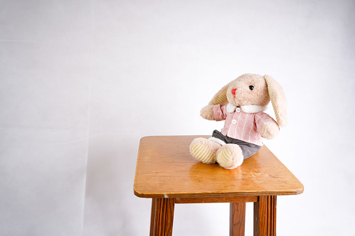 Toy brown plush rabbit sitting on a chair