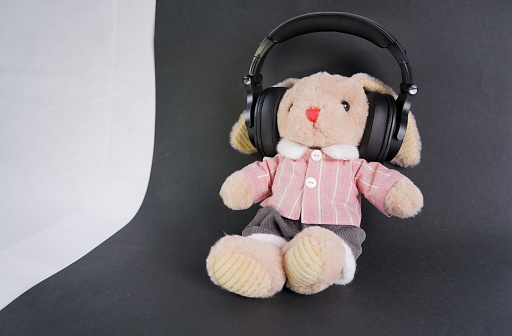 Toy brown plush rabbit on a black background with headphones