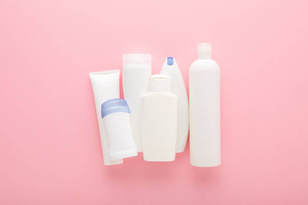 istock Different white plastic cosmetic bottles on light pink table background. Pastel color. Care about clean and soft body skin. Female daily beauty products. Closeup. Top down view. 2132063677