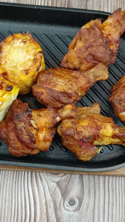 chicken drumsticks and grilled corn on a cast iron grill