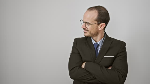 Smiling professional man with glasses and a suit standing against a white background