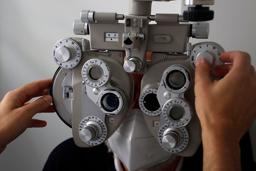 An ophthalmologist uses eyepiece to examine patient's eyes