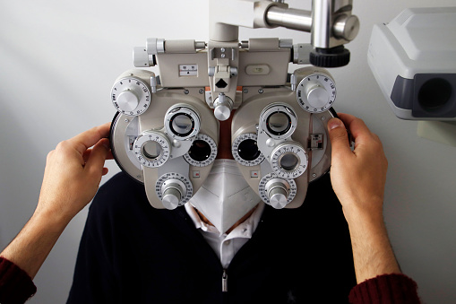 An ophthalmologist uses eyepiece to examine patient's eyes