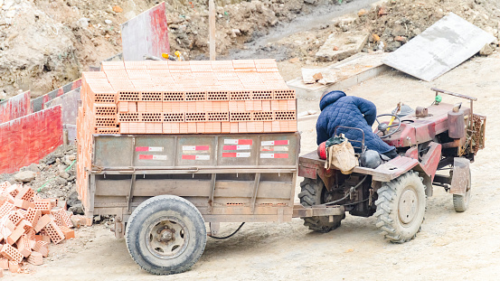 On a sunny day on March 6, 2024, a worker was unloading red bricks from a truck loaded with red bricks in Shuangliu District, Chengdu City, Sichuan Province