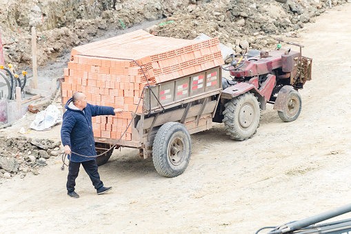 On a sunny day on March 6, 2024, a worker was unloading red bricks from a truck loaded with red bricks in Shuangliu District, Chengdu City, Sichuan Province